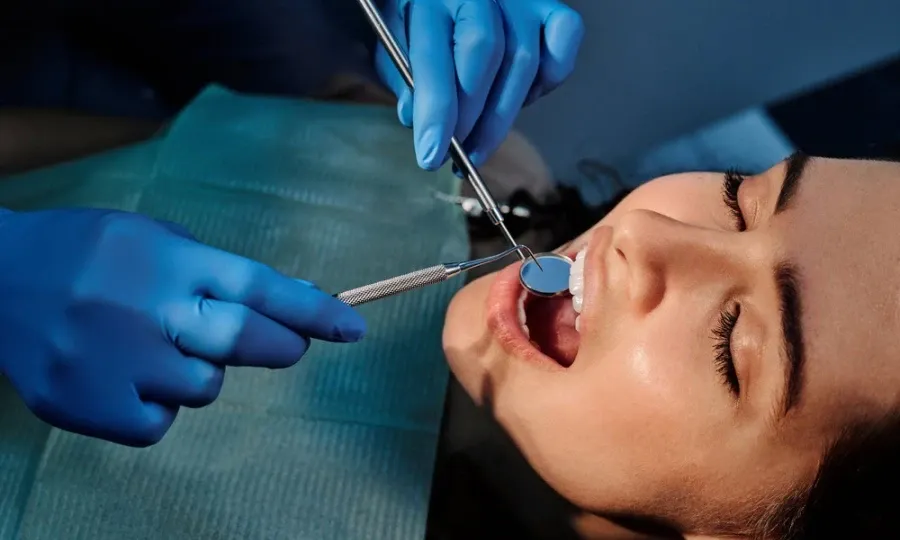 Dentist checking a patient's teeth for a cavity with a dental mirror